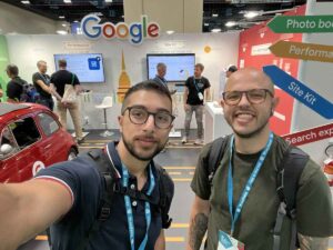 Due uomini sorridenti che si scattano un selfie allo stand Google Site Kit durante una conferenza sullo sviluppo web.